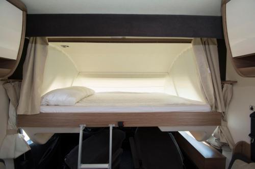 a small bed in the back of a room at Autocaravaning Menorca in Ferreries