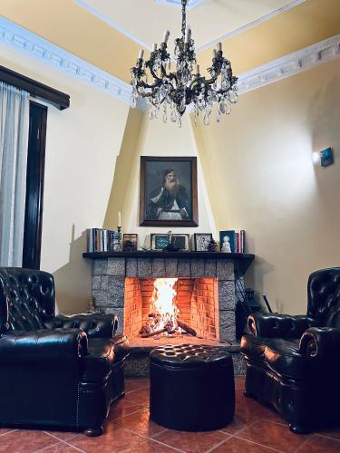 a living room with a fireplace with leather chairs and a chandelier at Panthoron Tzoumerka in Vourgareli