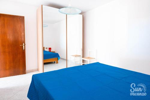 a bedroom with a blue bed and a mirror at Malamuri 5 sun vacanze in Budoni