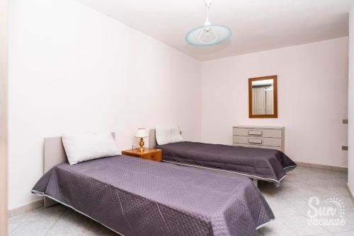 a bedroom with two beds and a mirror at Malamuri 4 sun vacanze in Budoni
