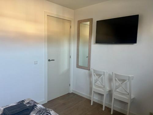 a bedroom with a tv on the wall and two chairs at BeachHouse AAN ZEE in Noordwijk aan Zee
