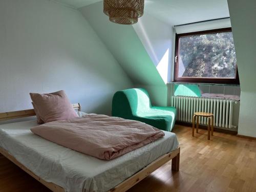 ein Schlafzimmer mit einem Bett, einem Stuhl und einem Fenster in der Unterkunft Schöne DG - Wohnung in Bonn in Bonn