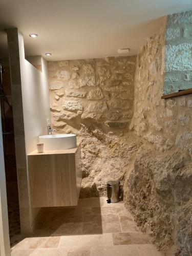une salle de bain avec un lavabo et un mur en pierre dans l'établissement Vialard, à Salignac Eyvigues