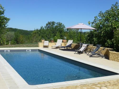 une piscine avec des chaises et un parasol dans l'établissement Vialard, à Salignac Eyvigues