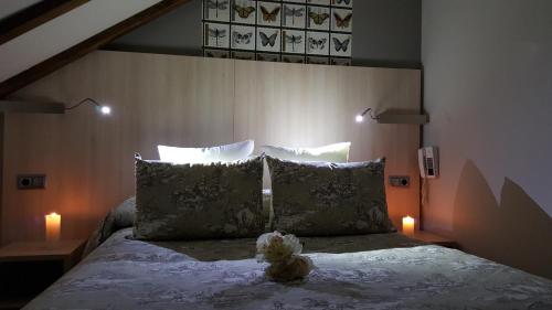 a teddy bear sitting on a bed with two candles at Hotel Presa in Riaño