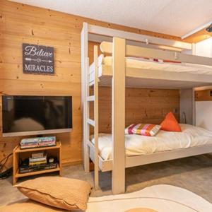une chambre avec deux lits superposés et une télévision à écran plat dans l'établissement Cozy Lodge by JP et Faby, à Val Cenis