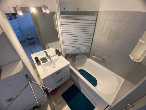 La salle de bains est pourvue d'une baignoire blanche, d'un lavabo et d'une douche. dans l'établissement Canet appartement à 100 m de la plage avec parking, à Canet