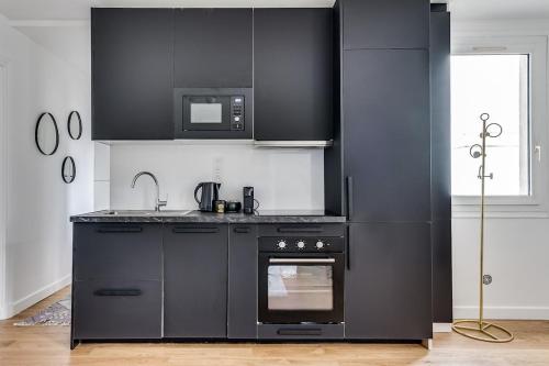 - une cuisine noire avec cuisinière et four micro-ondes dans l'établissement Intemporel, à Paris