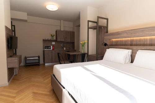 a bedroom with a large white bed and a kitchen at Residence Villa Bottacin in Trieste