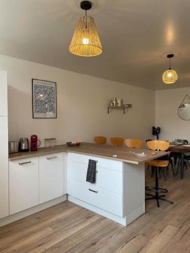 une cuisine avec des armoires blanches et une table avec des chaises dans l'établissement L'âme des Vignes Gîte Alsace, à Mittelbergheim