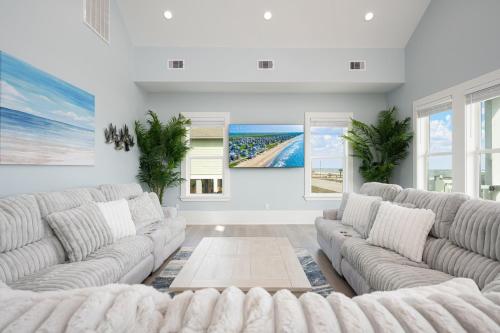 a living room with white couches and windows at Fins & Feathers home in Gilchrist