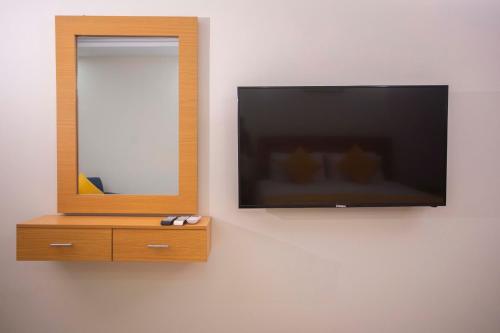 a television on a wall with a mirror and a dresser at Maati Spaces - Rooms with Kitchen in Lahore