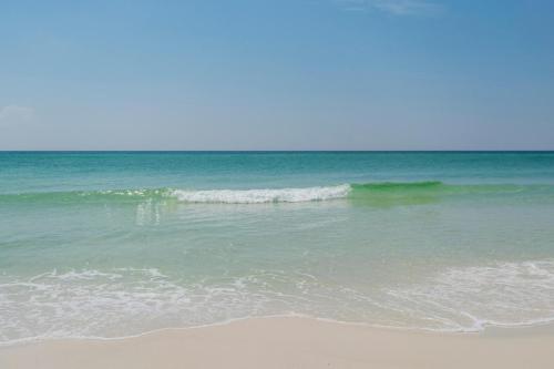 a beach with a small wave in the ocean at Whispering Sands #2b in Coffeyville