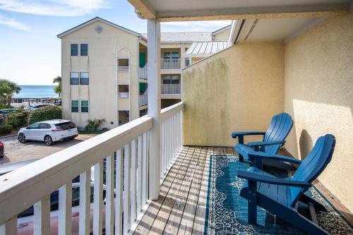 two blue chairs on a balcony with a view of the ocean at Whispering Sands #2b in Coffeyville