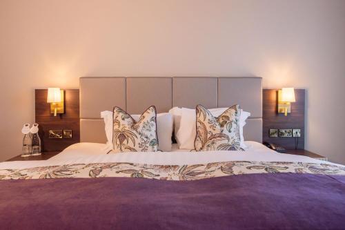 a bedroom with a large bed with pillows at Cork's Vienna Woods Hotel & Villas in Cork