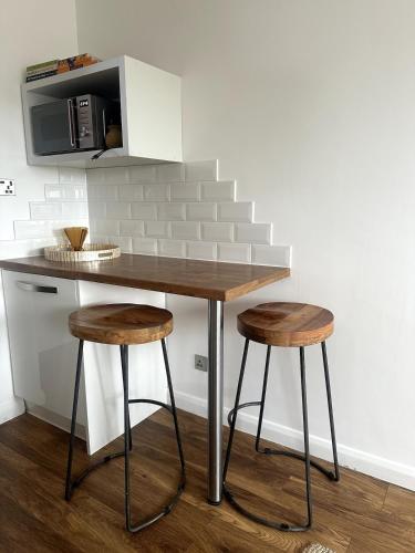 a kitchen counter with two stools and a microwave at Flat-on-Sea in Southend-on-Sea