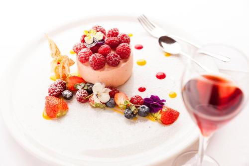 a dessert with berries on a plate next to a glass of wine at Granpanorama Hotel StephansHof in Villandro