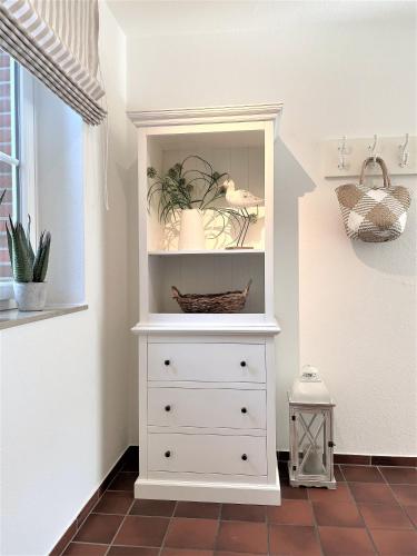 a white dresser with plants in a room at Frida SPO Ferienwohnung Nordsee mit Hund in Böhl