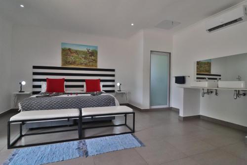 a bedroom with a large bed with red pillows at Kruger View Chalets in Malelane