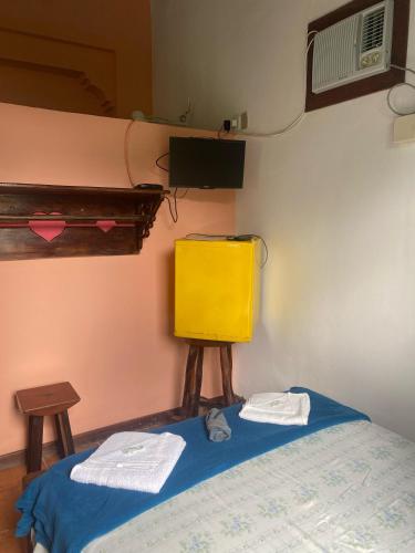 a bedroom with a bed and a yellow cabinet at Pousada e Camping Lumiar in Lençóis