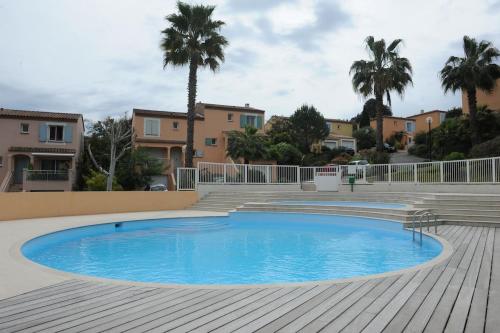 - une piscine avec une terrasse en bois et des palmiers dans l'établissement Apartment in park with pool, à Cannes