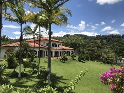 a house with palm trees in front of a yard at Espaço Eslovaquia - Casarão com Piscina, Paz e Conexão com a Natureza in Atibaia