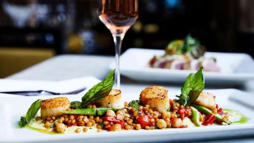 a plate of food on a table with a glass of wine at Kimpton Hotel Monaco Salt Lake City by IHG in Salt Lake City