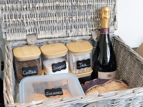 a basket with a bottle of wine and some food at Caedwalla House, Selsey in Selsey