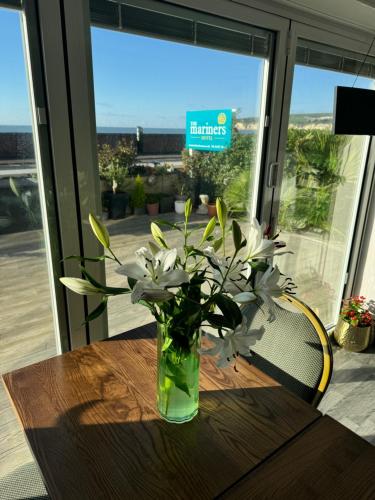 a vase of white flowers sitting on a wooden table at Mariners Hotel in Seaton