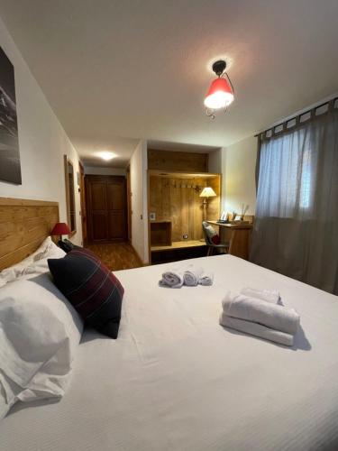 a bedroom with a white bed with towels on it at Hotel Coeur Du Village in La Thuile