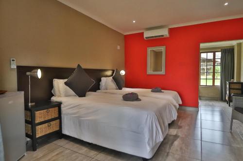 a bedroom with a large bed with a red wall at Kruger View Chalets in Malelane