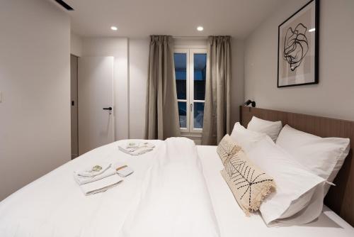 - un lit blanc avec des oreillers blancs dans une chambre dans l'établissement 2BR Apt with AC - ideal nest for families, à Paris