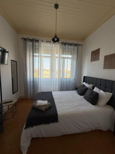 a bedroom with a large bed with a large window at Casa das Muralhas in Peniche