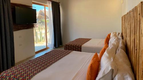 a bedroom with two beds and a tv and a window at Hotel Wayira Beach by On vacation in Ríohacha