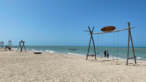 a swing on the beach with people in the water at Hotel Wayira Beach by On vacation in Ríohacha