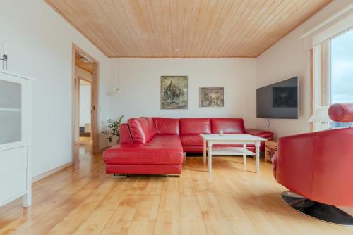 a living room with a red couch and a table at Lovely 5BR House in Tórshavn in Tórshavn