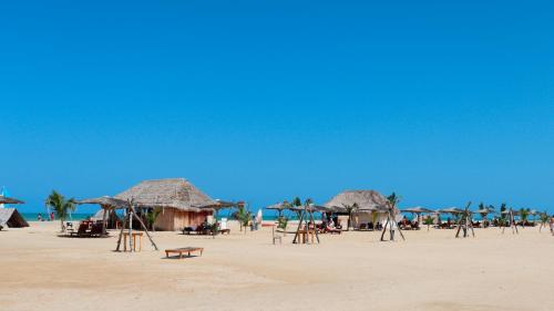 a beach with straw umbrellas and chairs on the beach at Hotel Wayira Beach by On vacation in Ríohacha
