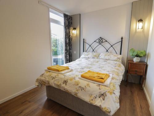 a bedroom with a bed with yellow sheets and a window at Swallow Cottage in Dumfries