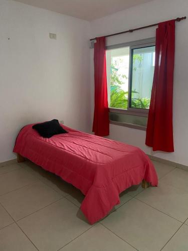 a red bed in a room with a window at Apart Hostel habitación con baño privado in Marcos Juárez