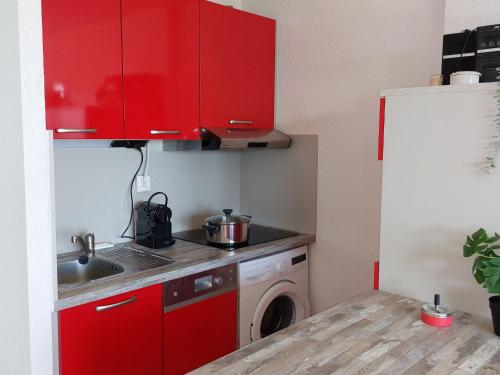 - une cuisine avec des placards rouges et un lave-linge dans l'établissement Apartment Dominica-2 by Interhome, au Barcarès