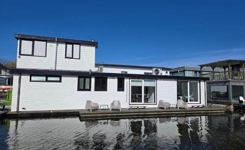 a house on a dock with chairs on the water at HouseBoat the New Lake - Nieuwe Meer in Amsterdam