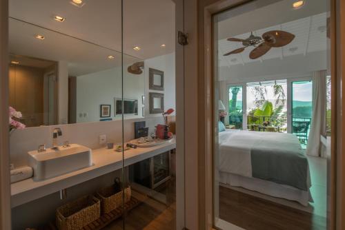 a bathroom with a sink and a bed and a mirror at Vila deste Hotel in Búzios