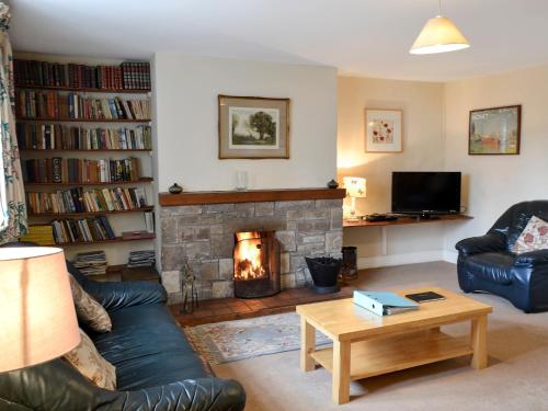 a living room with a fireplace and a couch at Honeysuckle Cottage - 23227 in Embleton