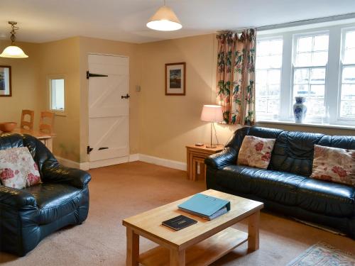 a living room with two leather couches and a table at Honeysuckle Cottage - 23227 in Embleton