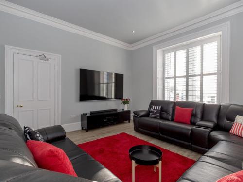 a living room with a black couch and a red rug at Holiday Home Portpatrick House by Interhome in Portpatrick