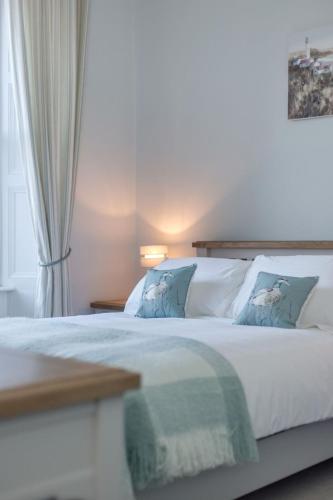 a bedroom with a large white bed with blue pillows at Holiday Home Portpatrick House by Interhome in Portpatrick