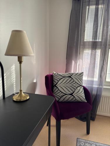 a lamp on a table next to a chair with a pillow at Hotelli Unelma in Kullaa