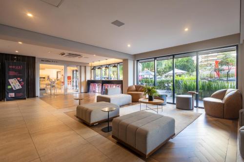 a living room with couches and tables and windows at Housi Faria Lima in Sao Paulo