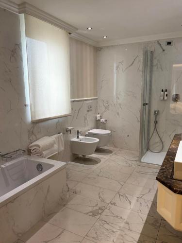 a bathroom with a tub and a toilet and a sink at Hotel Niccolo' V - Terme dei Papi in Viterbo