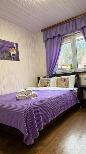 a bedroom with a purple bed with two towels on it at Гостинний двір" Живиця" ЧАН in Mizhhirʼʼya